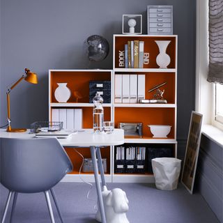 teal wall and home office and shelves and white desk with chair and orange desk lamp