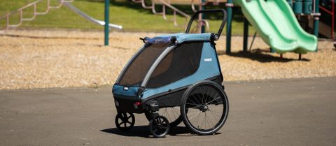 A Thule Courier bike trailer sits in a park