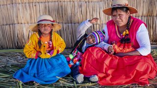 Seorang wanita dan dua anak kecil di pakaian tradisional yang penuh warna