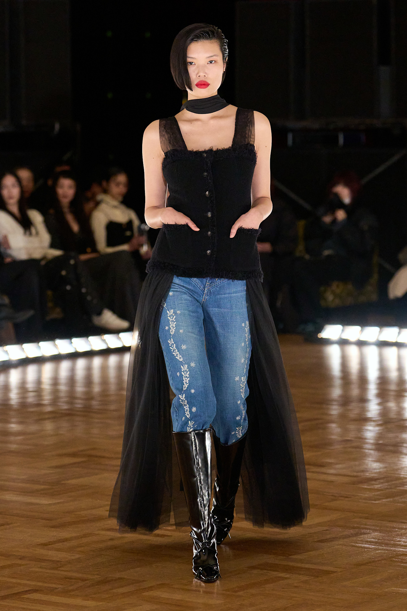 A runways image of shoes to wear with baggy jeans. The model wears straight leg baggies tucked into black knee-high boots.