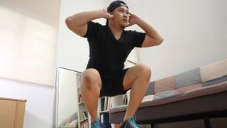 Man doing squat jumps at home