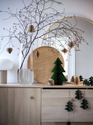 sideboard with Nordic style paper decorations, vase with twigs, table top tree decoration, mirror and light