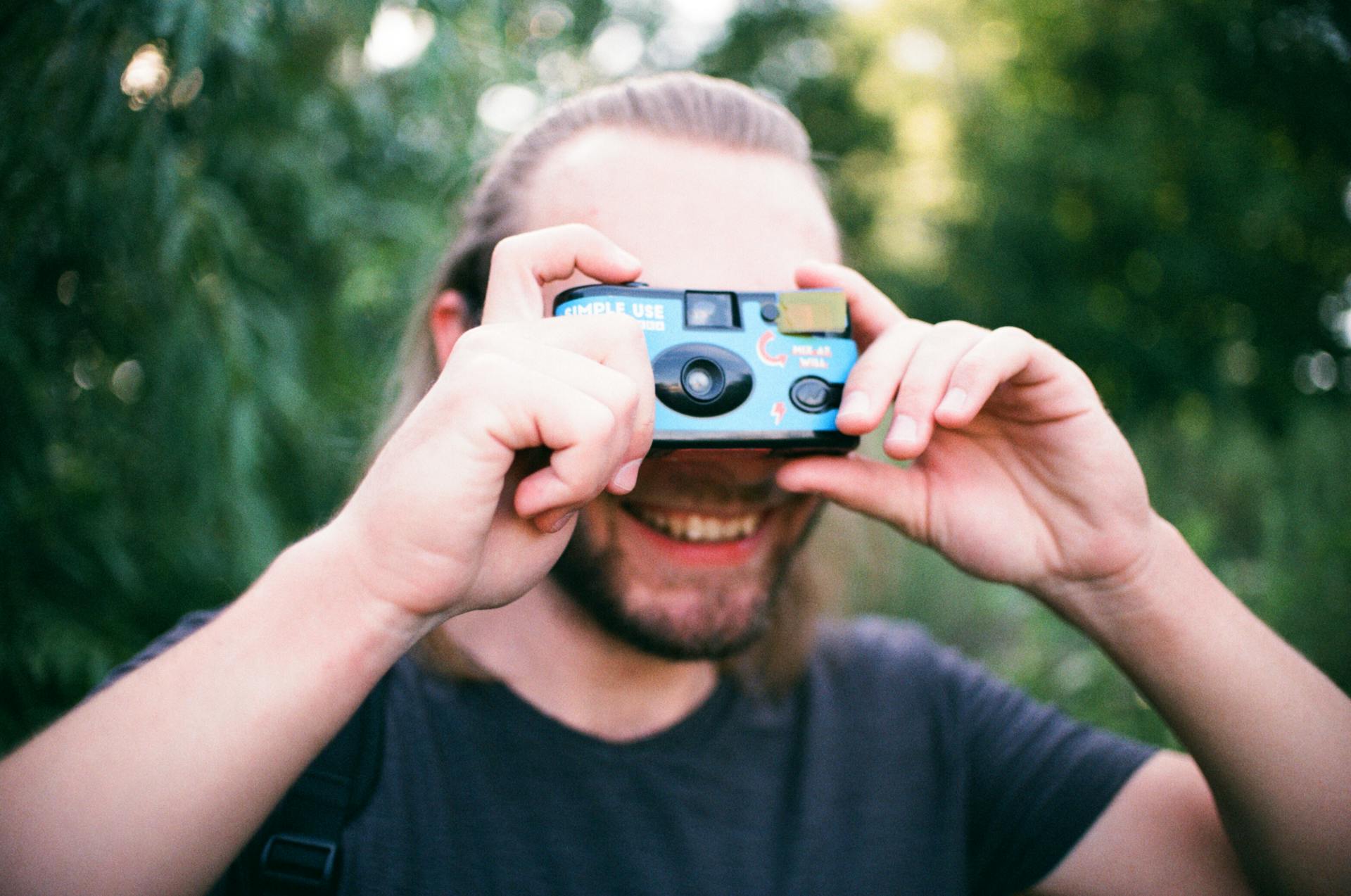 Man with beard taking photo with disposable camera