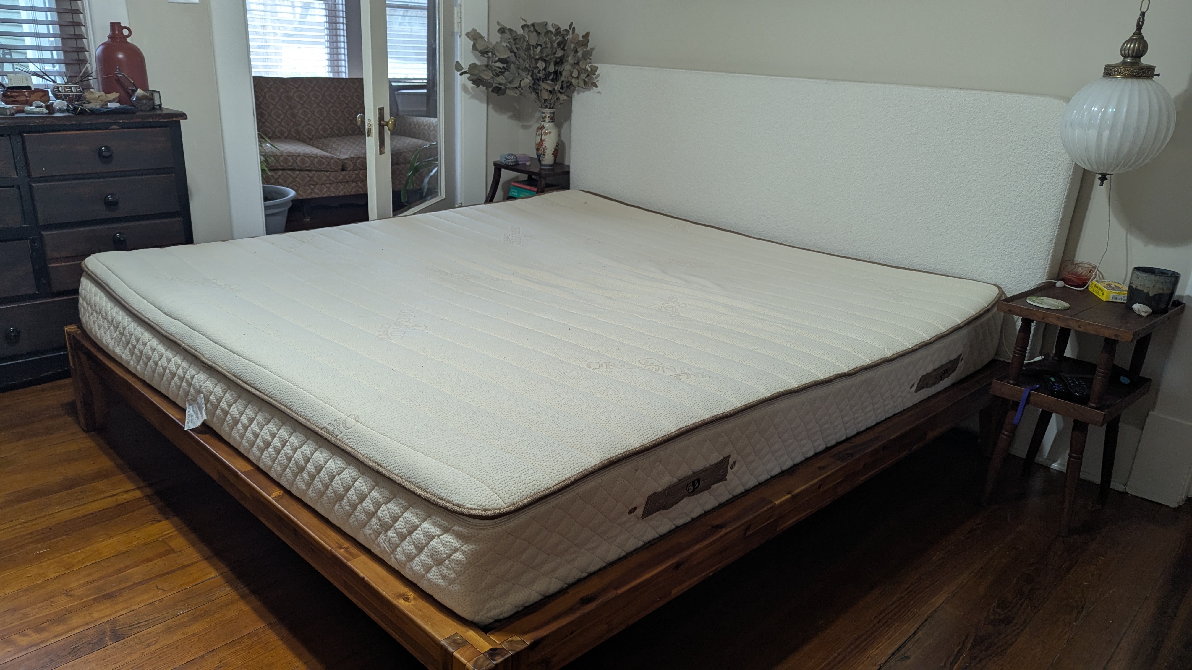 The Plushbeds Botanical Bliss mattress set up on a wooden bed frame in the middle of a bedroom