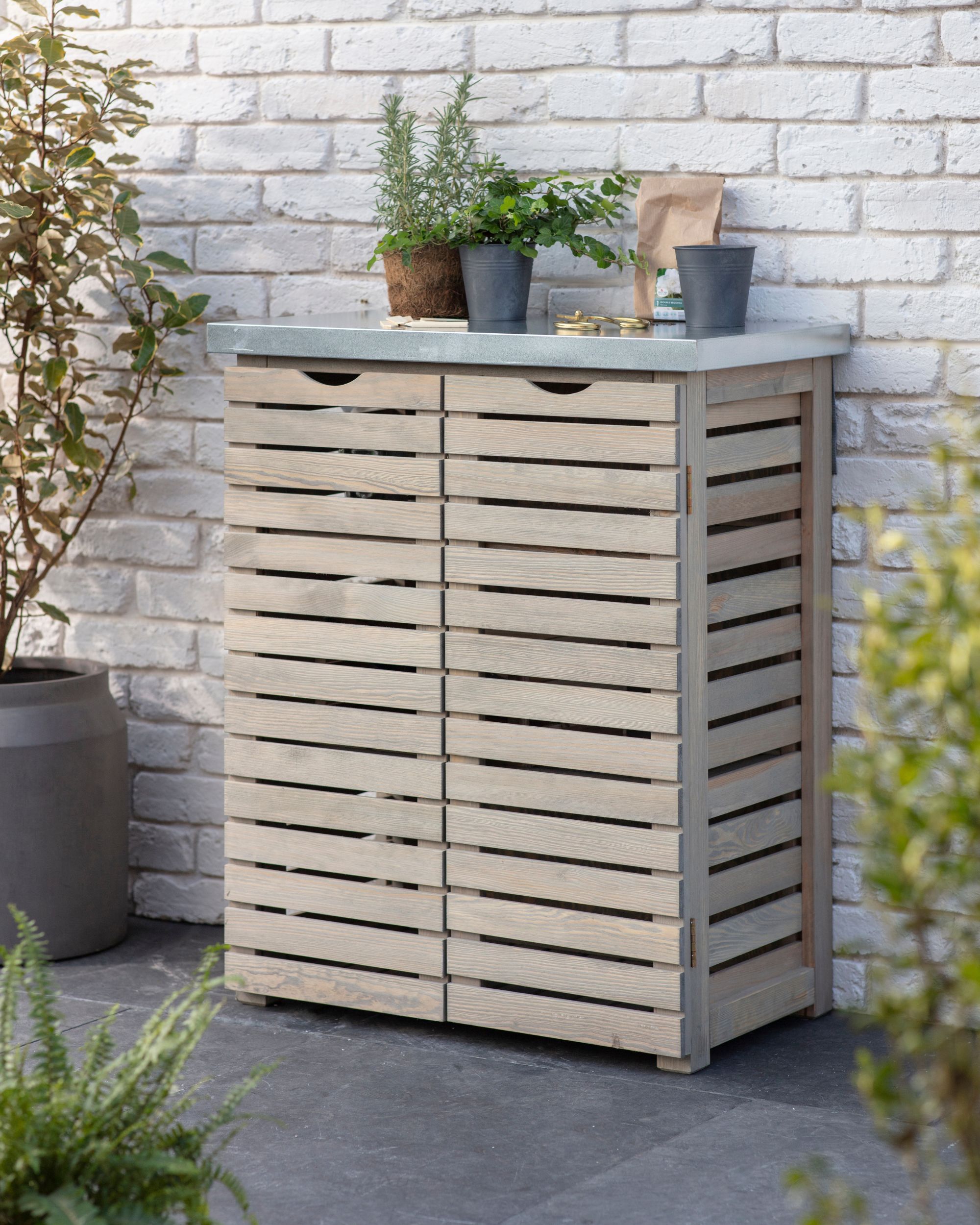 Wooden slatted outdoor storage unit with a metal worktop.