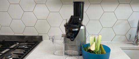 Kuvings B1700 on a kitchen countertop with a bowl of fruit and vegetables