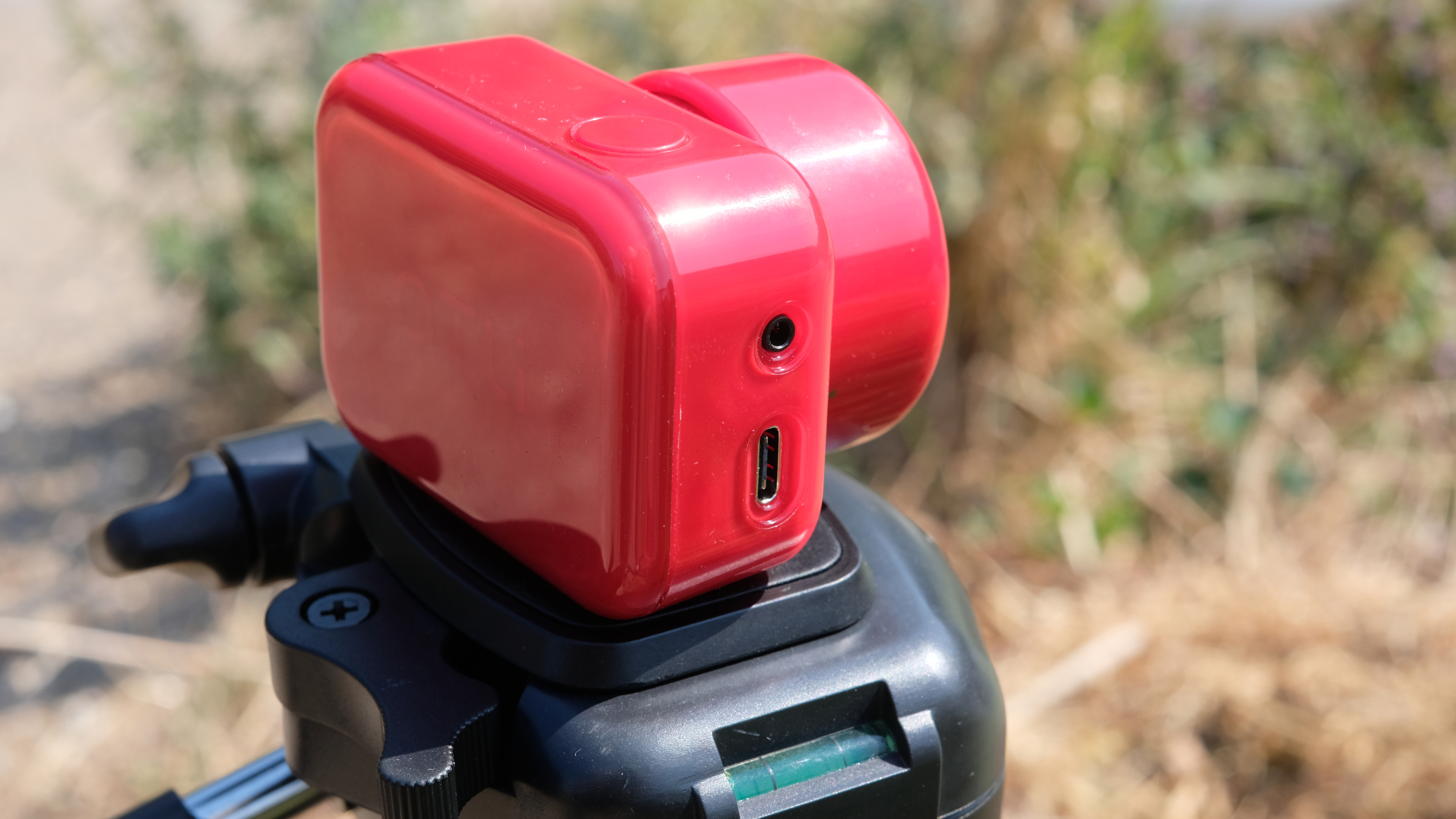 Photograph of the ATLi Eon time-lapse camera in red mounted on a tripod