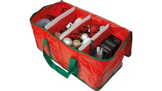 An opened red and green plastic organizer bag with four large compartments filled with Christmas decorations, for ornament storage containers.