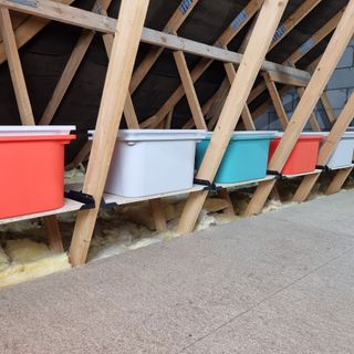 Colourful storage boxes on wooden ledges above insulation in loft