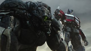 Still from the movie Transformers: Rise of the Beasts. Here we see Optimus Primal (robot gorilla) and Optimus Prime (truck in robot mode) standing side by side.