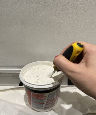 tile adhesive being stirred by hand on white background