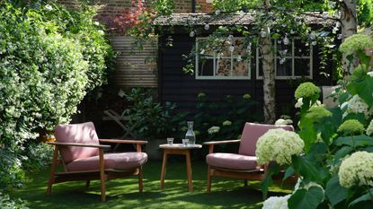 How to make a small garden look bigger: small garden with pink sitting and black shed