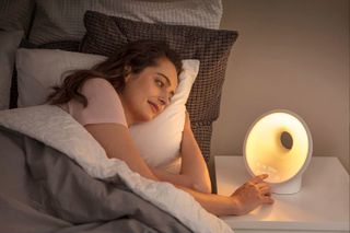 Woman in bed with wake-up light on her bedside table