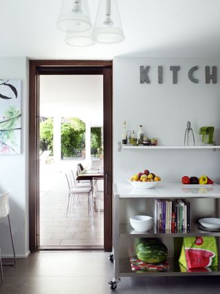 A white kitchen with a wooden doorway leading onto an outdoor dining space