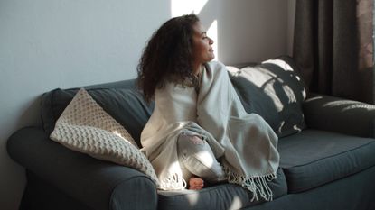 Seasonala affective disorder: a woman sat on her couch in winter
