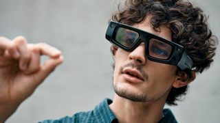 Man wearing Snap Spectacles 5, interacting with an unseen AR element using hand gestures