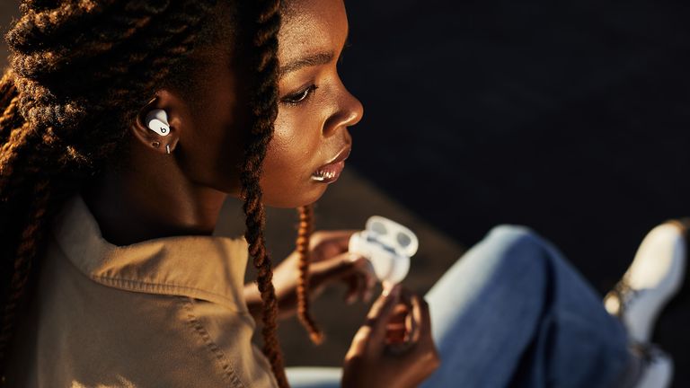 Best true wireless earbuds 2021, Beats Studio Buds being worn by a woman, with the case in her hand