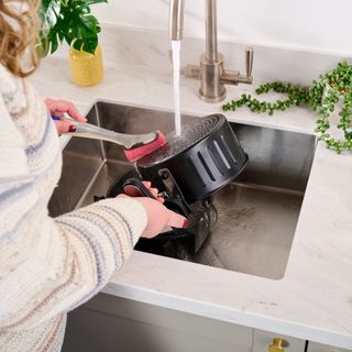 air fryer insert being hand washed in kitchen sink