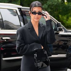 Kourtney Kardashian wears oval sunglasses and a black blazer