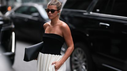 Sofia Richie wearing a black, strapless top, white skirt and sunglasses in New York