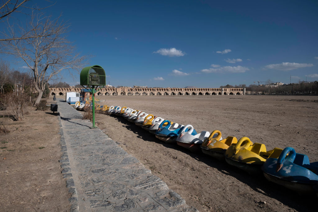 Swan-shaped boats lie on the dried-up riverbed of the Zayandeh Rud River as the Si-o-se-pol (33-Bridge) historical bridge is seen in the background in Isfahan, Iran, on February 22, 2025.