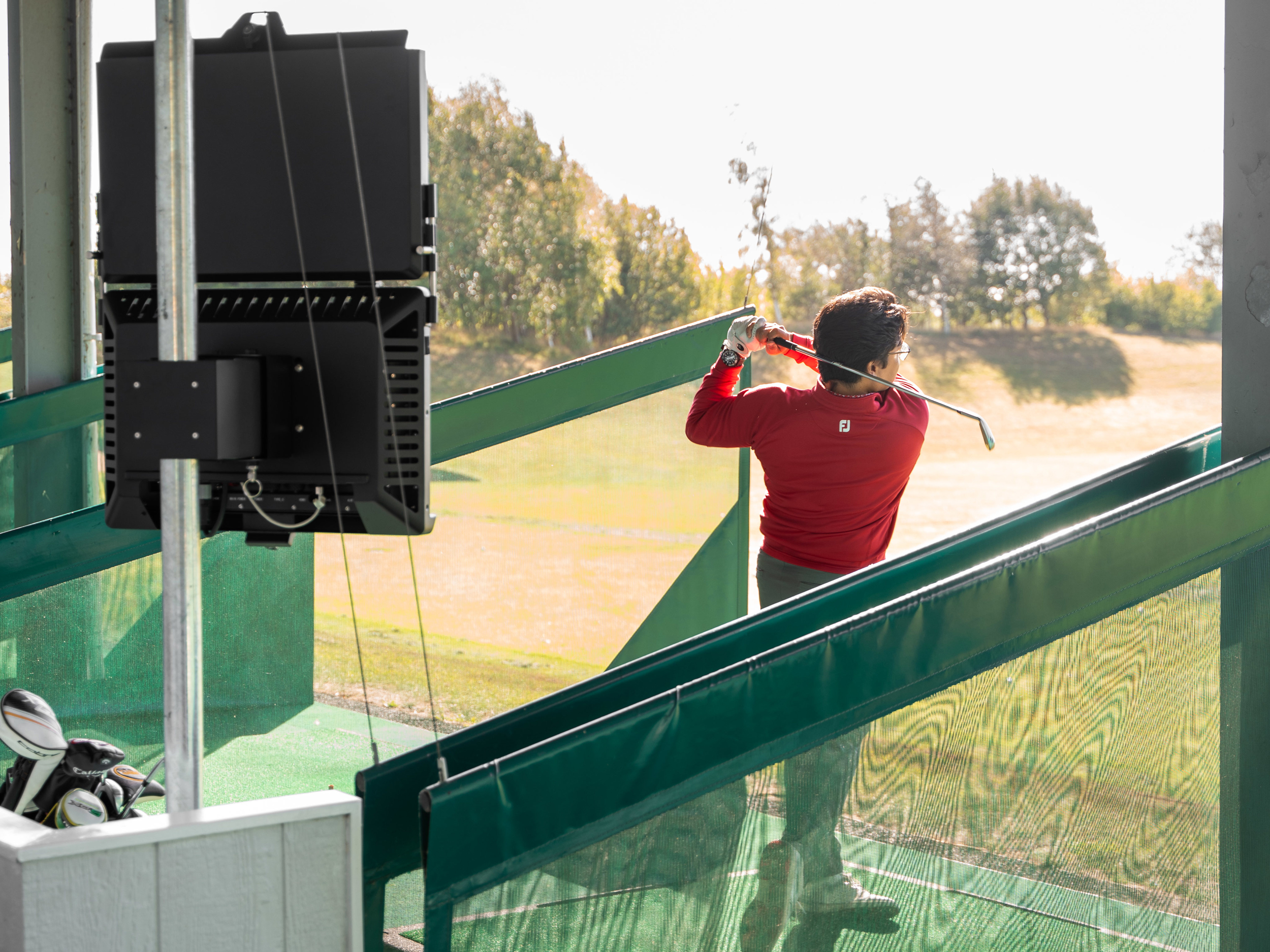 A golfer holds their finish on a driving range