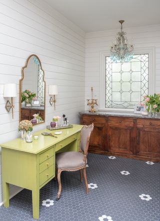 dressing room with bright yellow dressing table, grey tiled floor, gold mirror, vintage sideboard and shiplap walls