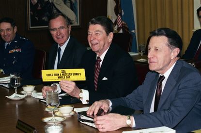 President Reagan Holding Up Bumper Sticker During Meeting