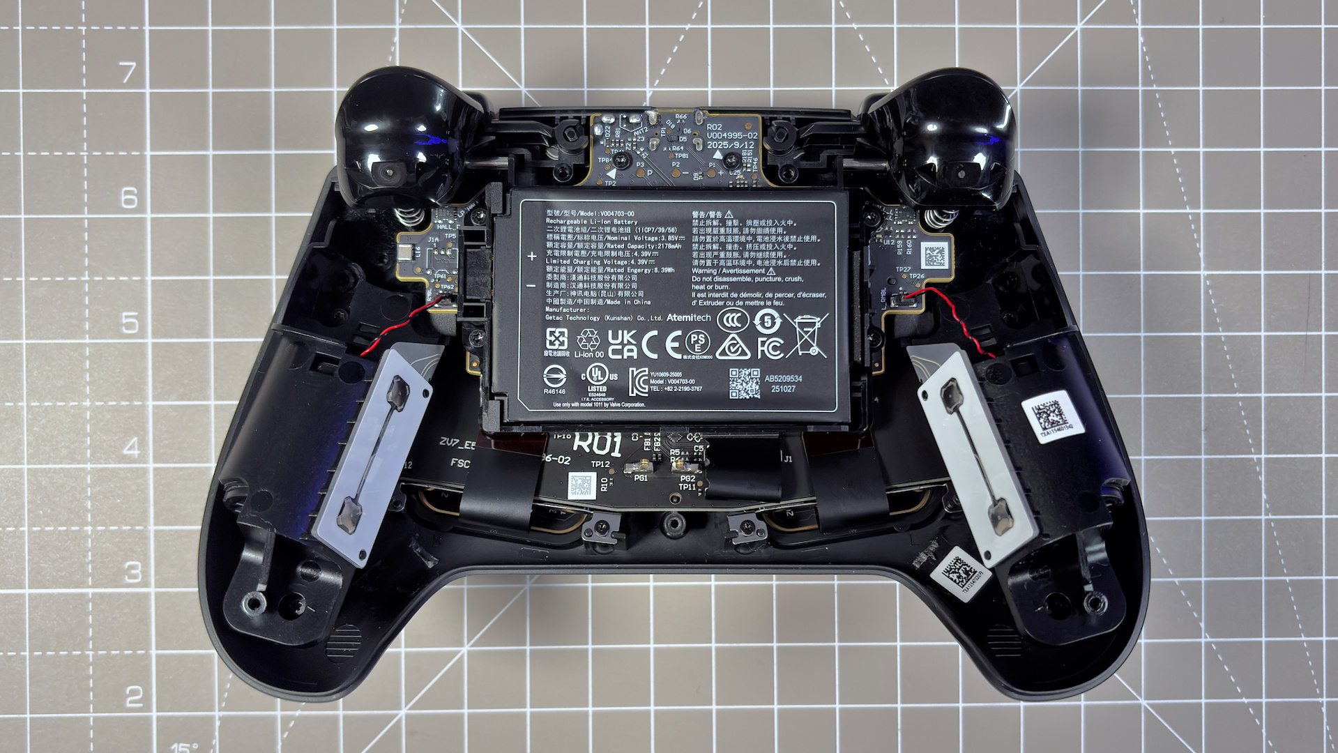 The Steam Controller on a desk during a teardown, with various parts removed.