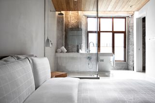 Open plan bathroom and bedroom of hotel with grey finishings