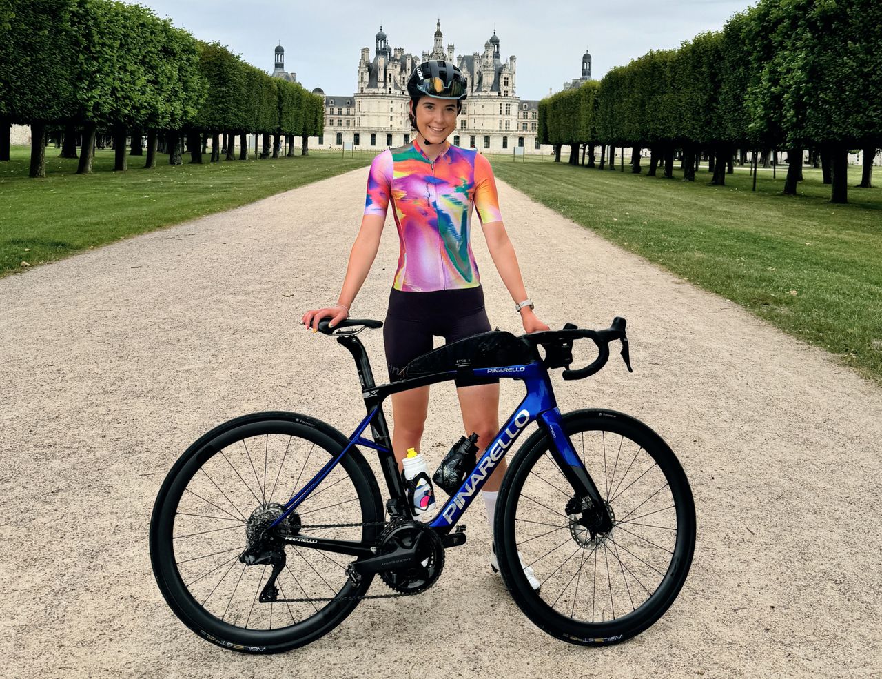 Amy Hudson holding a Pinarello bike in front of the Château de Chambord