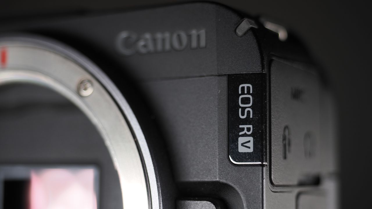 Canon EOS R50 V on a wooden surface, against a dark background