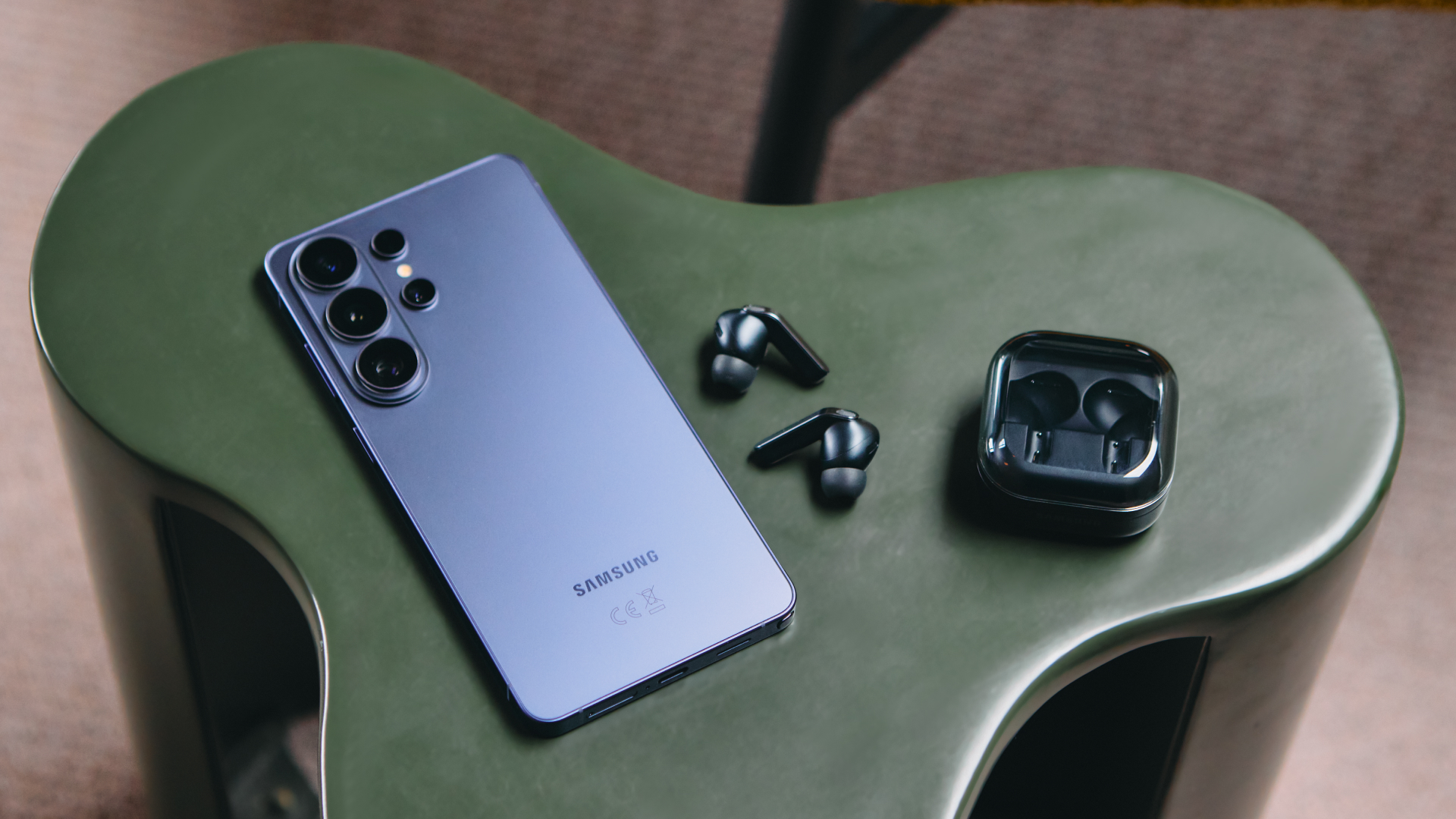 A Samsung Galaxy S26 Ultra and Samsung Galaxy Buds4 Pro on a green table.