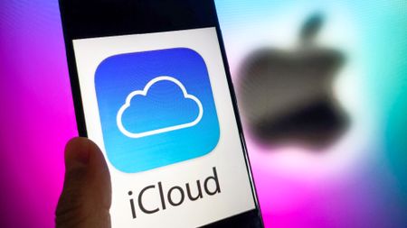 Apple iCloud logo on a smartphone, with Apple logo in the background