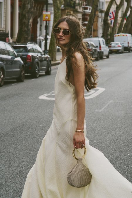 Women in white dress with sunglasses and accesory bag