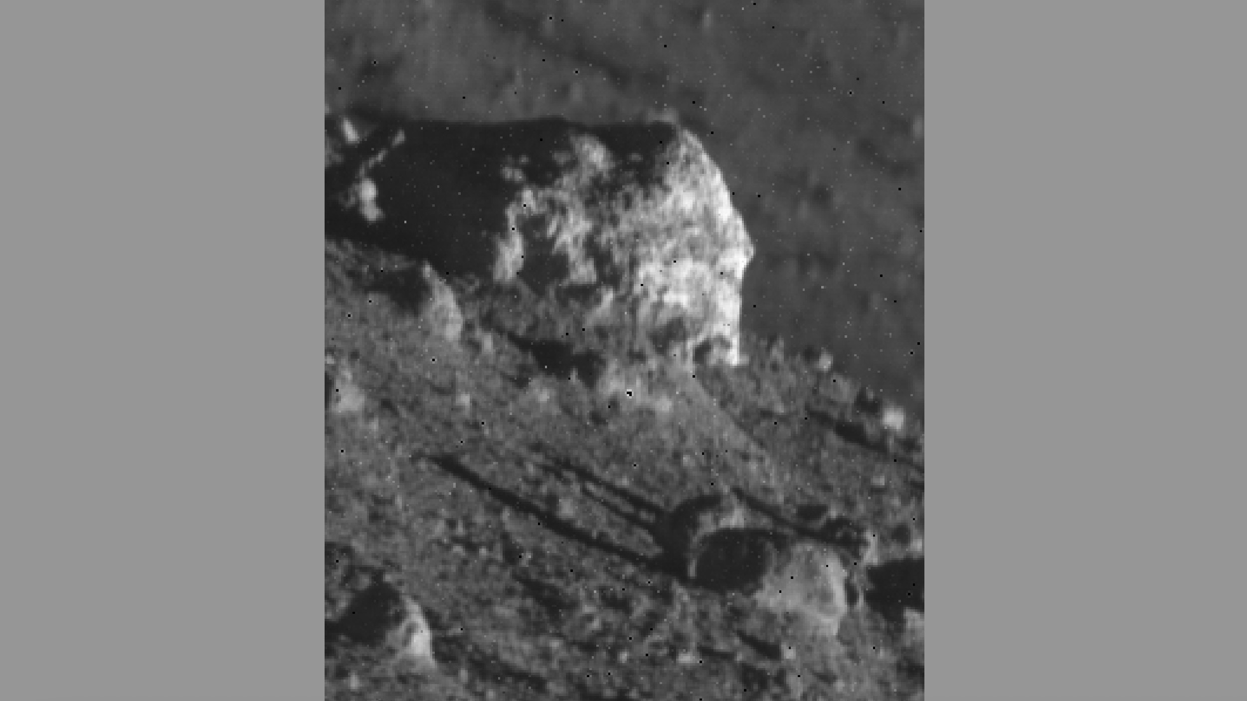 Uma visão aproximada de uma grande rocha na superfície da Lua, cercada por rochas menores.