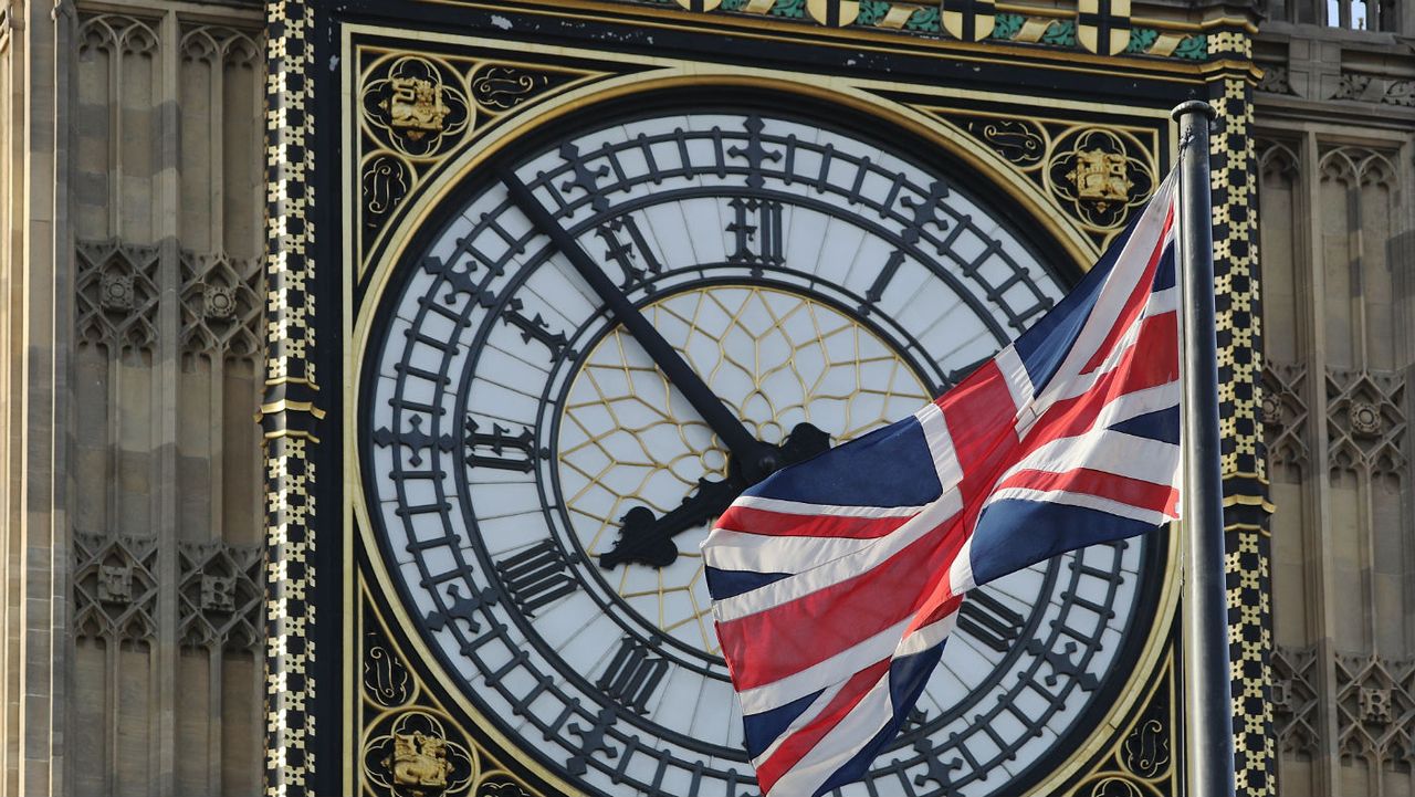 A Union Flag flies in front of the clockface of Elizabeth Tower 