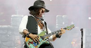 Joe Perry of Aerosmith plays onstage with Alice Cooper with a green, offset doublecut with a reverse headstock.