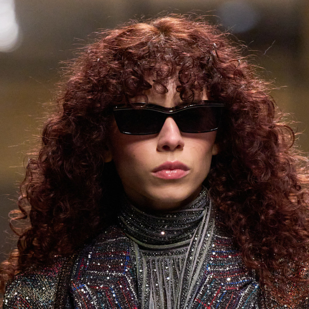 Model with curly red hair wearing sunglasses