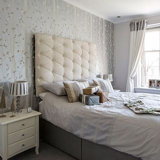 bedroom with wallpaper wall and white headboard and side table