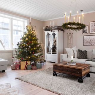 christmas living room with decorated tree, vintage dresser and ceiling light wreath