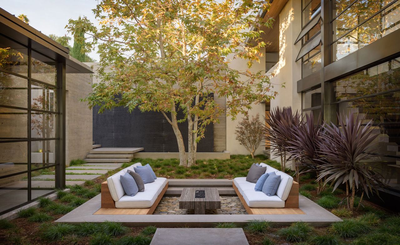 a stylish sunken outdoor seating area in a backyard