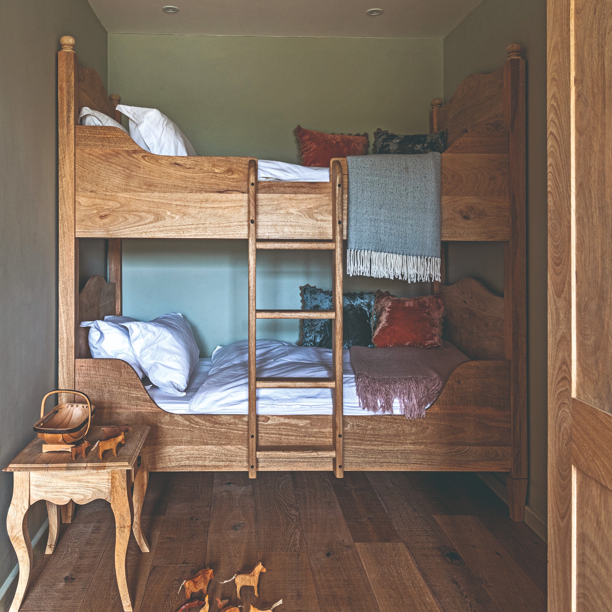 A light green-painted box room with rustic dark-wood bunk beds