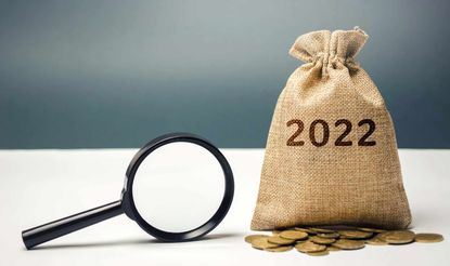 Photo of magnifying glass and money sack labeled 2022 