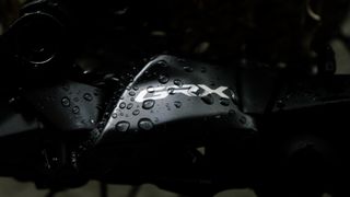 A close up of a dark grey rear derailleur with water drops on it