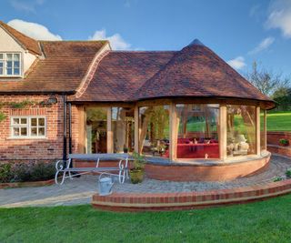 round faceted garden room style oak frame extension attached to brick built house