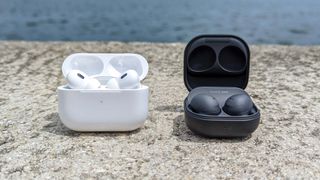 AirPods Pro 2 and Samsung Galaxy Buds 2 Pro side-by-side on a wall outside by a waterway
