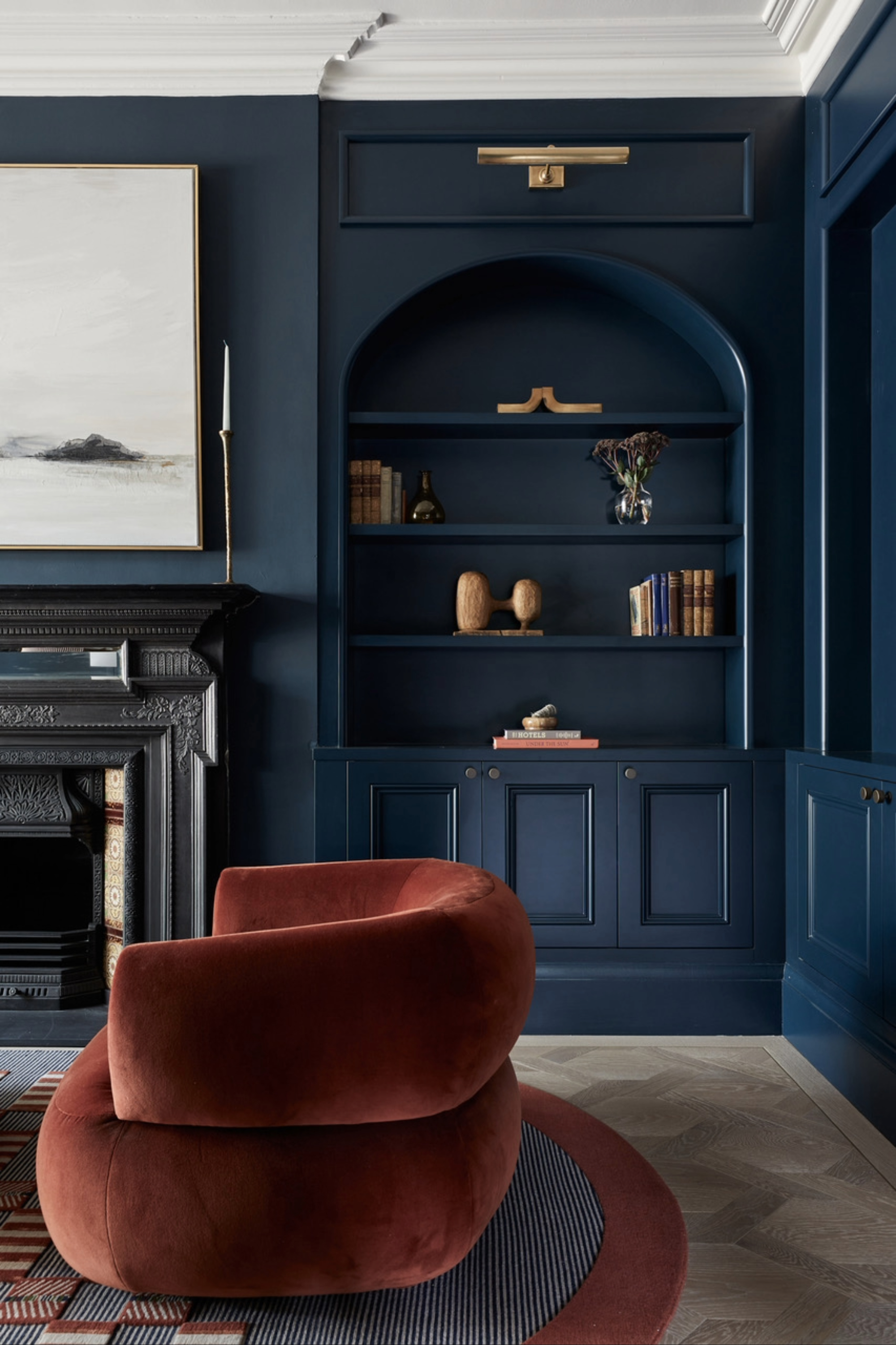 A living space colour-drenched with bold blue walls offset by a rust-hued armchair.