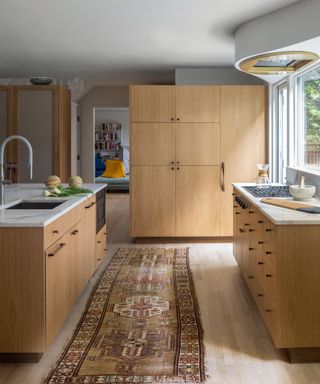 kitchen with vintage rug natural wood cabinets and marble worktops