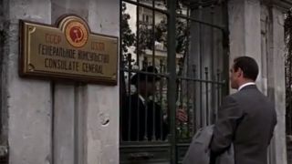 Sean Connery in a suit with his back to the camera, standing at the gate of a Soviet embassy in From Russia With Love.